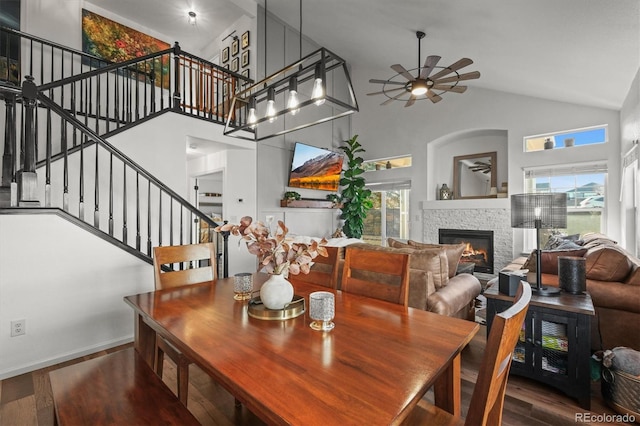 dining area featuring stairs, a stone fireplace, wood finished floors, and a wealth of natural light