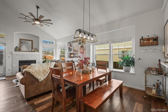 dining area with plenty of natural light, a stone fireplace, and wood finished floors