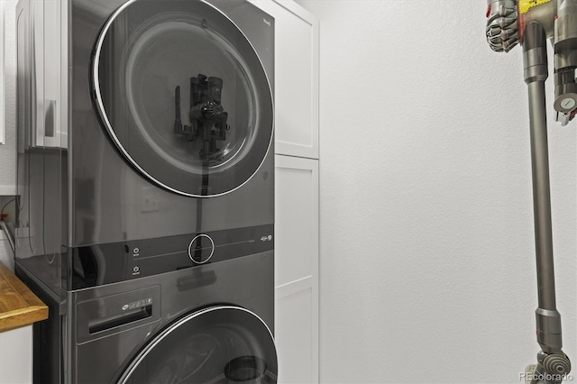 laundry room with cabinet space and stacked washer / drying machine