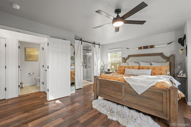 bedroom with ceiling fan, a barn door, ensuite bath, and wood finished floors