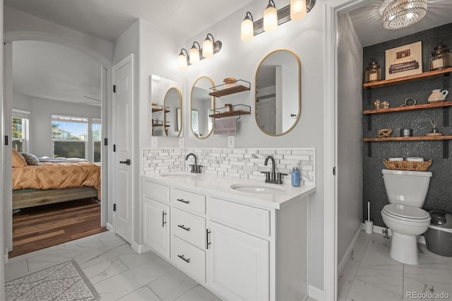 ensuite bathroom featuring tasteful backsplash, marble finish floor, a sink, and ensuite bath