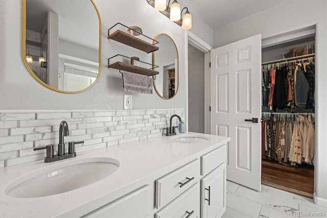 full bath featuring a walk in closet, marble finish floor, a sink, and double vanity