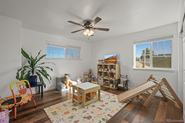 playroom with a wealth of natural light, dark wood finished floors, and baseboards