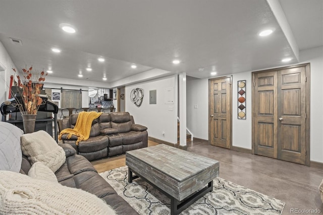 living area with finished concrete flooring, recessed lighting, visible vents, and baseboards