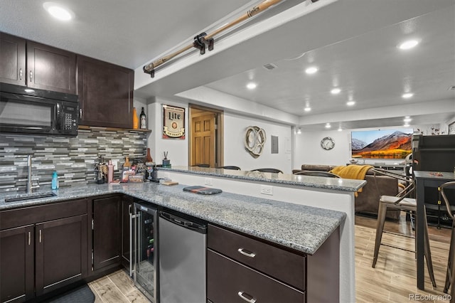 kitchen with tasteful backsplash, light wood-style flooring, a peninsula, fridge, and black microwave