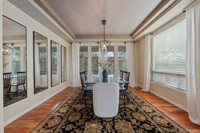 7408 Sodalite Way, Castle Rock, CO 80108 - dining room featuring a tray ceiling, plenty of natural light, wood finished floors, and a chandelier