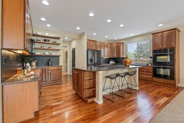 7408 Sodalite Way, Castle Rock, CO 80108 - kitchen with open shelves, refrigerator with ice dispenser, a breakfast bar, a center island, and light wood-style flooring