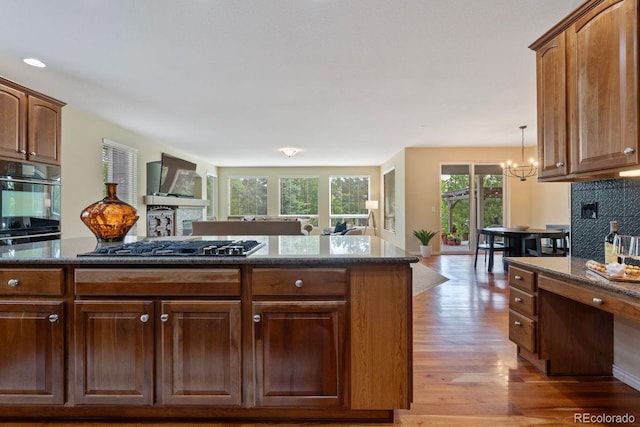 7408 Sodalite Way, Castle Rock, CO 80108 - kitchen with light wood-style floors, open floor plan, a chandelier, dark stone counters, and a fireplace