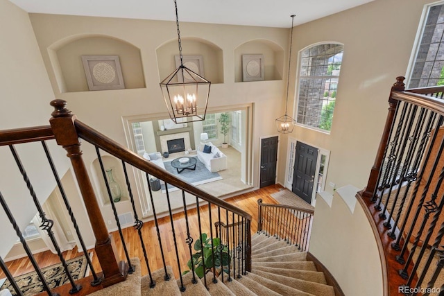 7408 Sodalite Way, Castle Rock, CO 80108 - stairway featuring wood finished floors, a high ceiling, plenty of natural light, and a chandelier