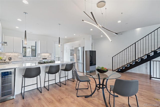 dining room featuring recessed lighting, light wood-style floors, stairway, and wine cooler