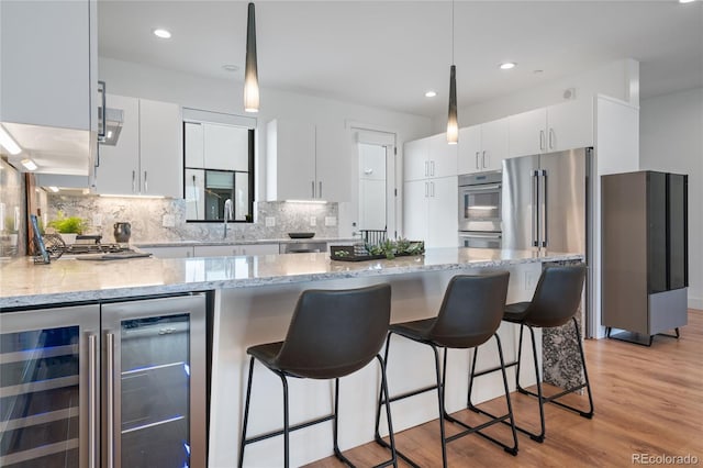 kitchen featuring wine cooler, appliances with stainless steel finishes, decorative light fixtures, and white cabinets