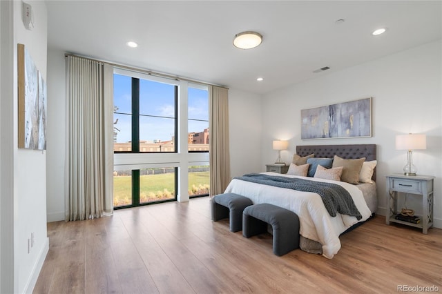 bedroom featuring baseboards, recessed lighting, wood finished floors, and multiple windows