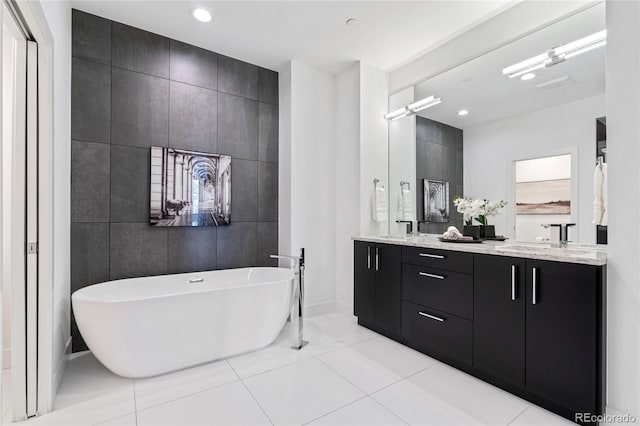 full bathroom with double vanity, a freestanding tub, a sink, baseboards, and recessed lighting