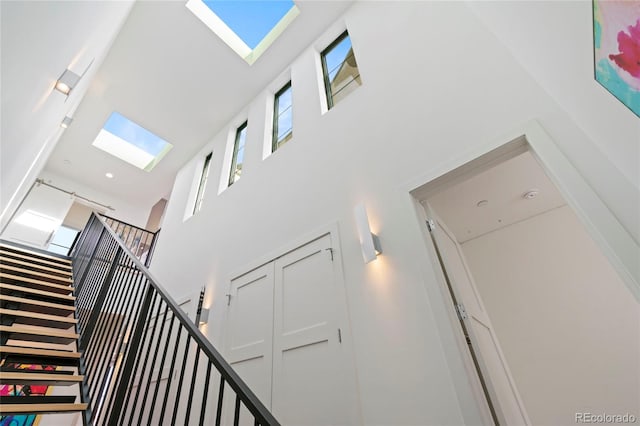 staircase featuring a high ceiling and a skylight
