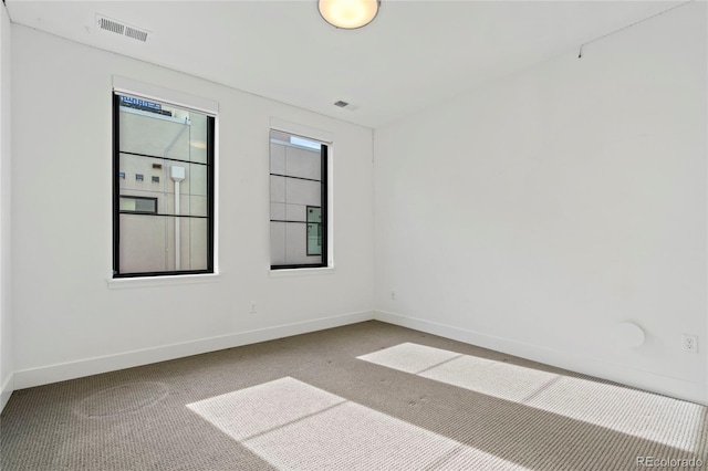 carpeted spare room featuring visible vents and baseboards