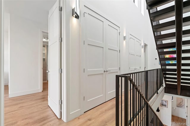 corridor with baseboards and light wood-style floors