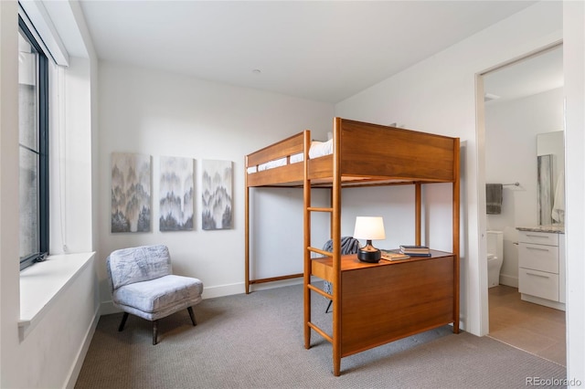 carpeted bedroom featuring baseboards and connected bathroom