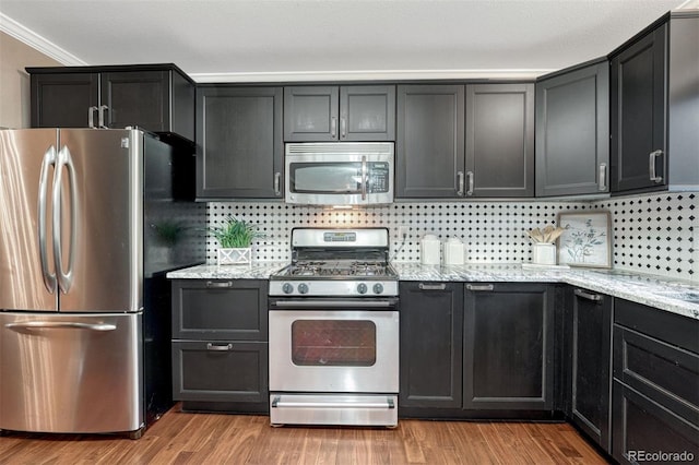 123 Wheat Ridge St, Palmer Lake, CO 80133 - kitchen with stainless steel appliances, light stone countertops, tasteful backsplash, light wood-type flooring, and crown molding