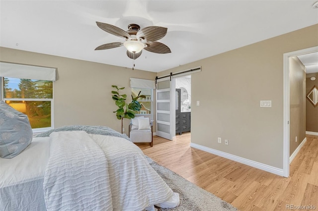 123 Wheat Ridge St, Palmer Lake, CO 80133 - bedroom with a barn door, light wood-type flooring, and a ceiling fan
