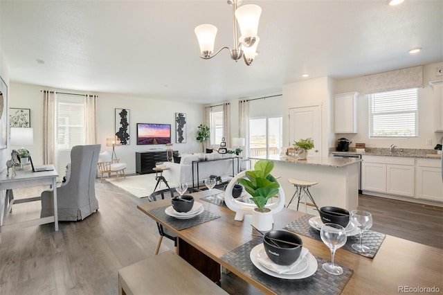 dining area featuring hardwood / wood-style flooring, sink, and a chandelier