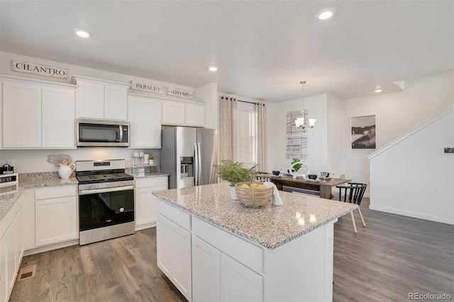 kitchen featuring stainless steel appliances, white cabinetry, pendant lighting, and dark hardwood / wood-style flooring