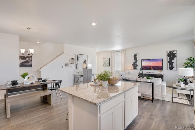 kitchen with pendant lighting, white cabinetry, a chandelier, hardwood / wood-style flooring, and light stone countertops