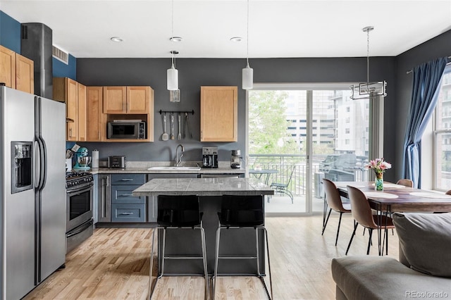 1440 Little Raven St Unit 202, Denver, CO 80202 - kitchen featuring stainless steel appliances, a sink, light wood-type flooring, and a kitchen island