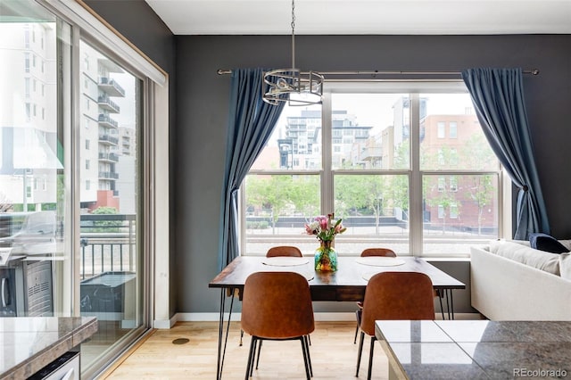 1440 Little Raven St Unit 202, Denver, CO 80202 - dining space with a chandelier, plenty of natural light, light wood-style flooring, and baseboards