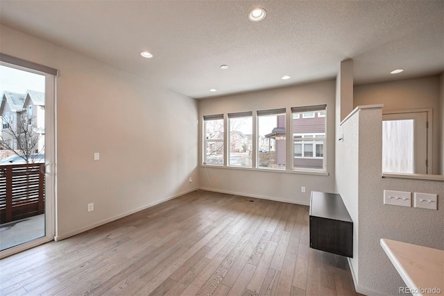 unfurnished living room with light hardwood / wood-style flooring and a textured ceiling