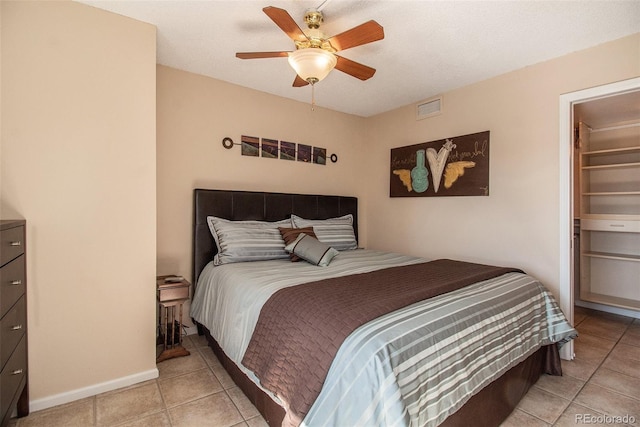 tiled bedroom featuring a closet, ceiling fan, a walk in closet, and a textured ceiling