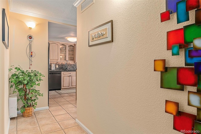 hall featuring a textured ceiling, crown molding, sink, and light tile patterned floors