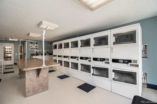 laundry area with washing machine and clothes dryer, a textured ceiling, and stacked washer / drying machine