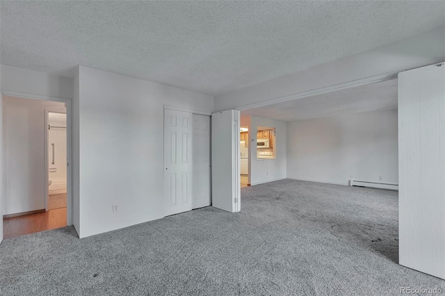 carpeted empty room with a baseboard radiator and a textured ceiling