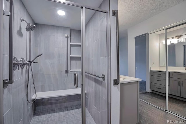 bathroom with vanity, an enclosed shower, and a textured ceiling