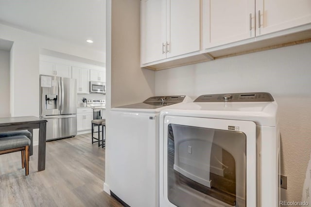 laundry area with light wood-type flooring, cabinets, and independent washer and dryer