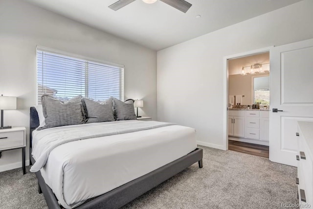 bedroom with ensuite bathroom, light colored carpet, and ceiling fan