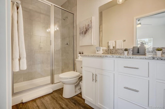 bathroom featuring toilet, hardwood / wood-style flooring, vanity, ceiling fan, and walk in shower