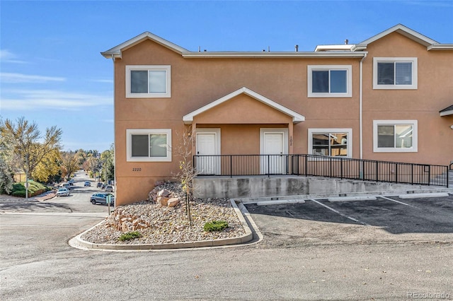 view of property featuring uncovered parking and stucco siding