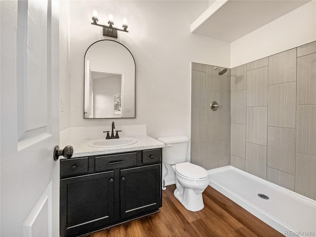 bathroom featuring vanity, toilet, hardwood / wood-style flooring, and tiled shower