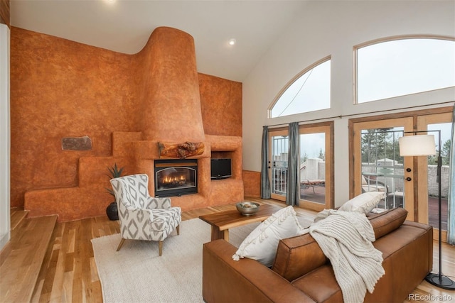living area featuring recessed lighting, a tile fireplace, high vaulted ceiling, and wood finished floors