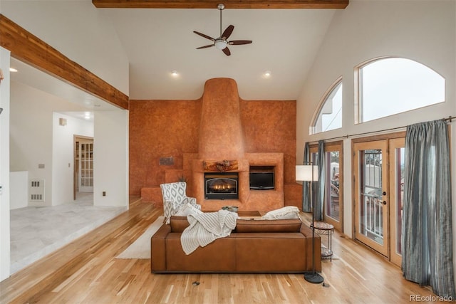 living room with a fireplace, light wood-type flooring, high vaulted ceiling, and a ceiling fan