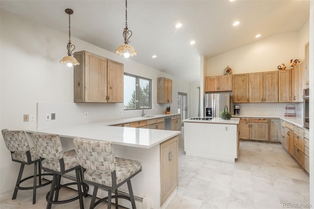 kitchen with light countertops, stainless steel appliances, a peninsula, and a sink