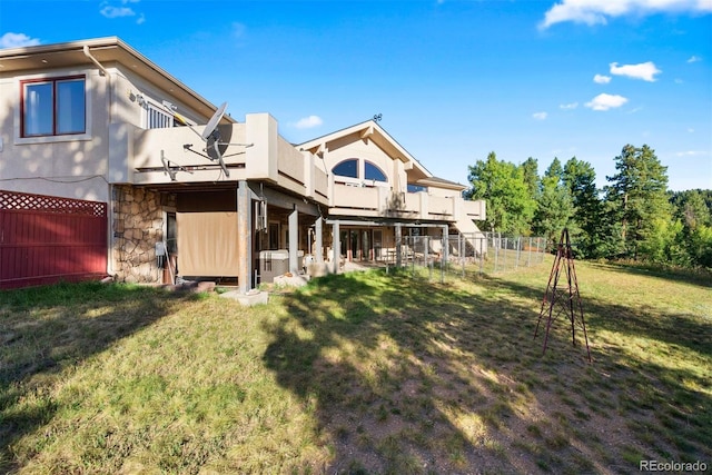 back of house featuring a yard, a fenced backyard, and a balcony