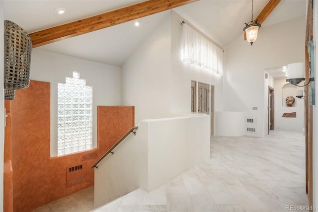 hallway featuring arched walkways, an upstairs landing, visible vents, and vaulted ceiling with beams