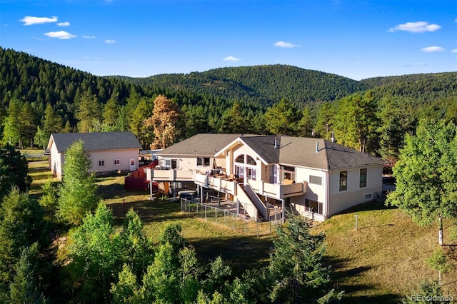 back of house featuring a forest view and a deck with mountain view
