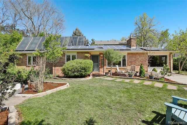 view of front of property featuring brick siding, a front yard, solar panels, a standing seam roof, and a chimney