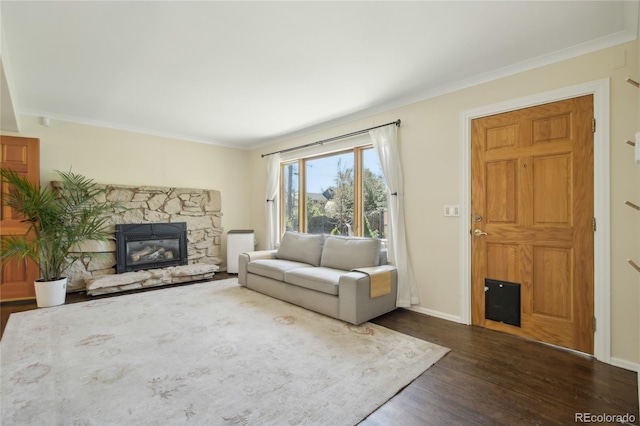 living room featuring dark wood-type flooring, a fireplace, ornamental molding, and baseboards