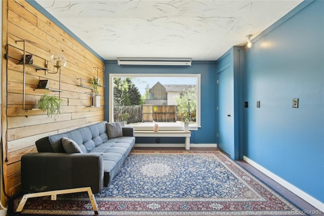 living area featuring wood walls, baseboards, and crown molding