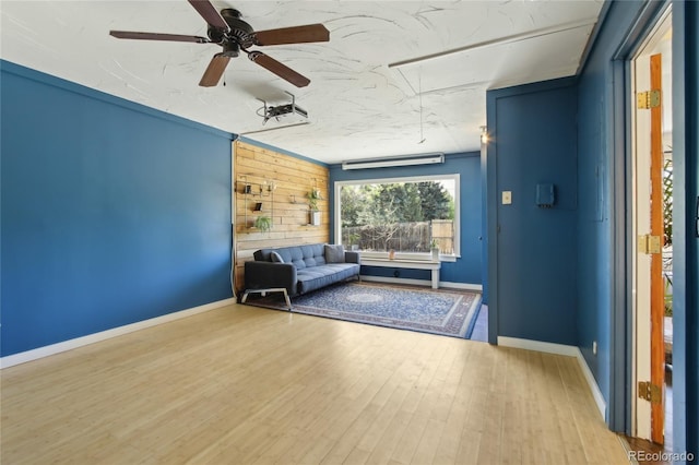 living area featuring attic access, wood finished floors, ceiling fan, and baseboards
