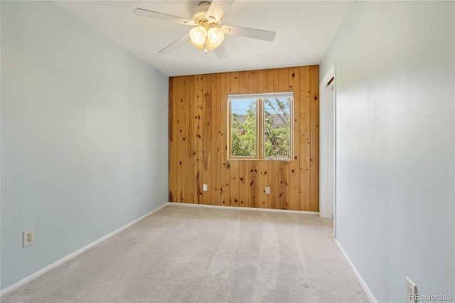 spare room with wood walls, baseboards, a ceiling fan, and carpet floors